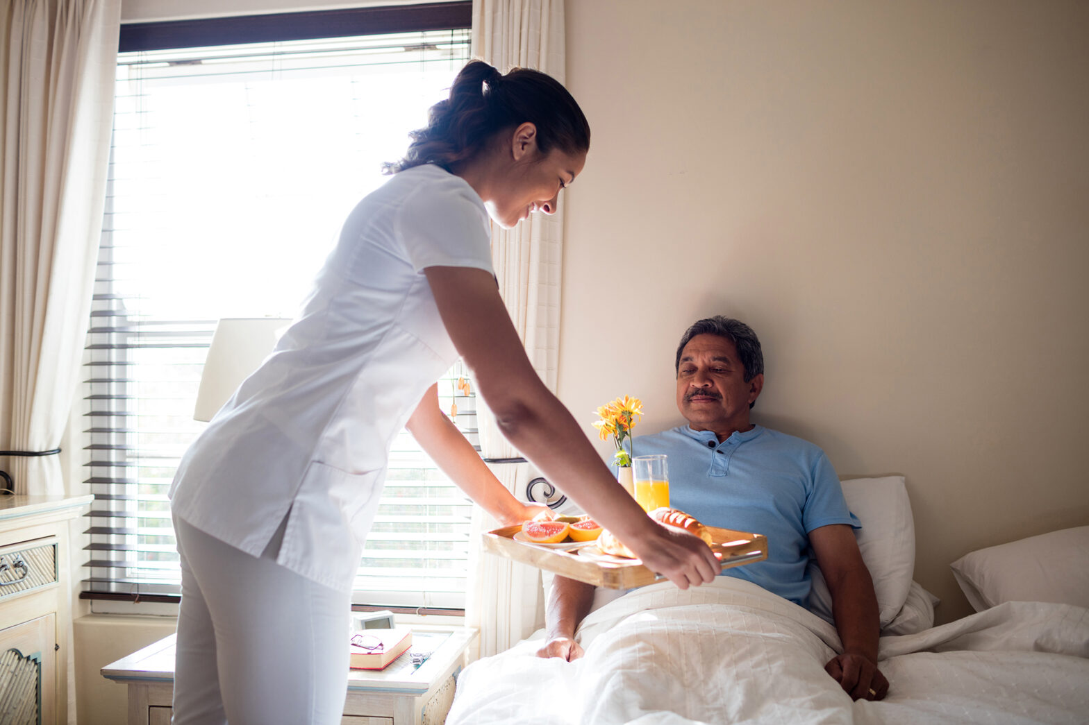 Doctor serving breakfast to senior patient in bedroom