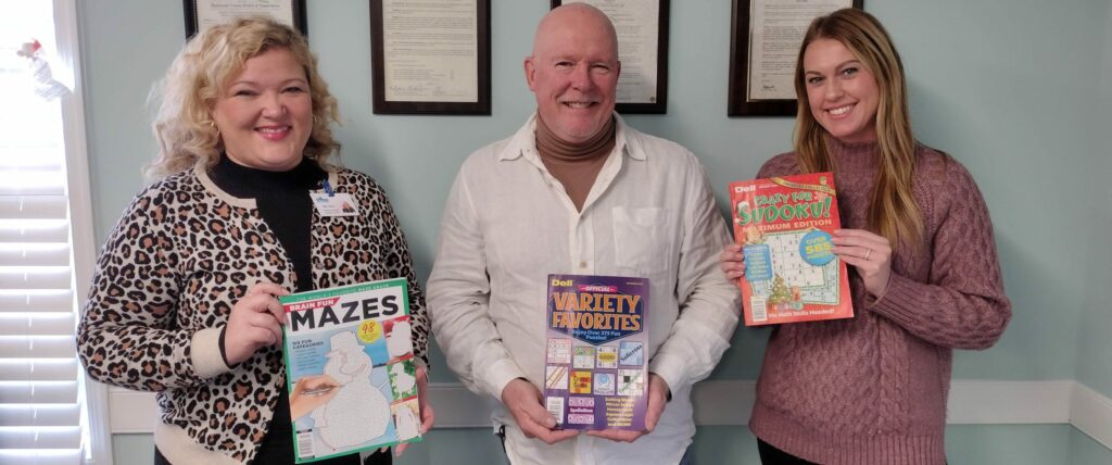 Three people holding puzzle books