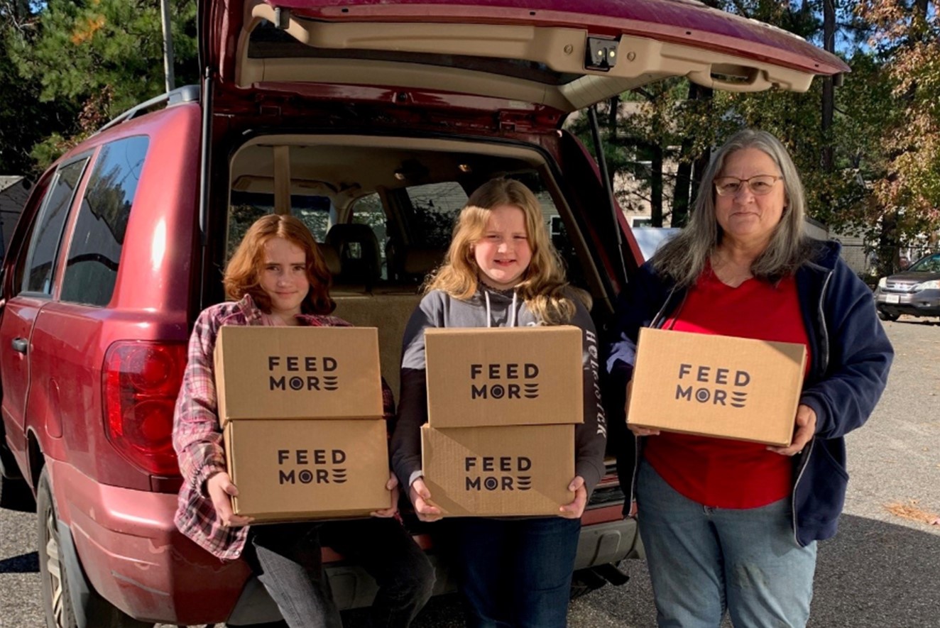 Three volunteers carrying boxes of food