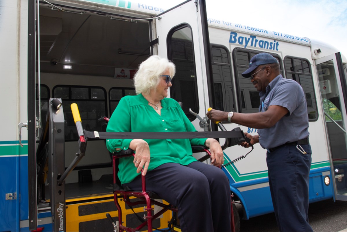 Bus driver helps client using wheelchair to board a bus