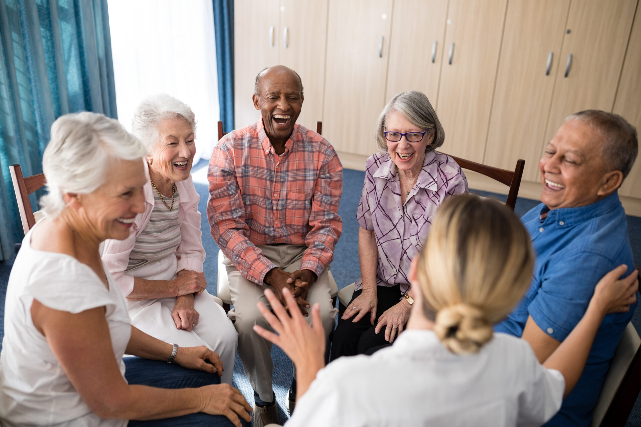 Cheerful older adults sitting with female health worker